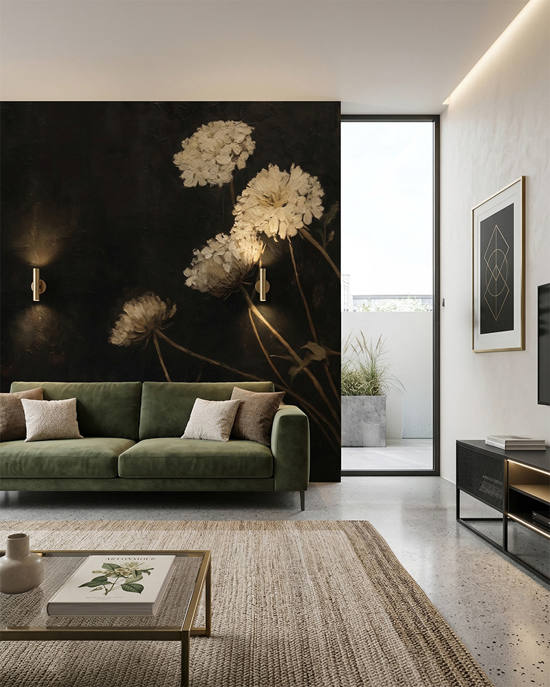 Nowoczesny salon z ciemną fototapetą przedstawiającą duże, białe kwiaty o malarskiej strukturze na czarnym tle. Przed ścianą stoi oliwkowa, aksamitna sofa, a obok rośnie figowiec dębolistny.