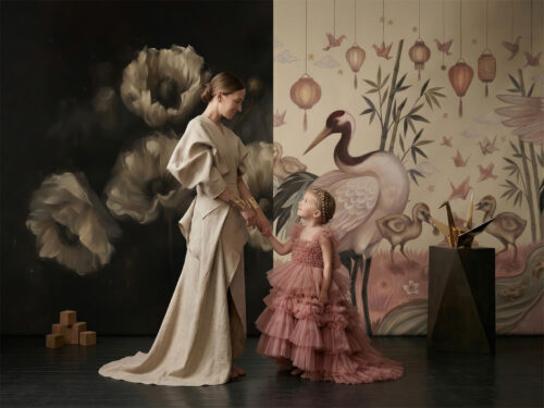 Luksusowa fototapeta na fizelinie. Lewa strona z ciemnym tłem i artystycznymi białymi makami, prawa jasna w stylu chinoiserie z żurawiami, lampionami i bambusem. Na pierwszym planie kobieta i dziewczynka w eleganckich strojach trzymają się za ręce.